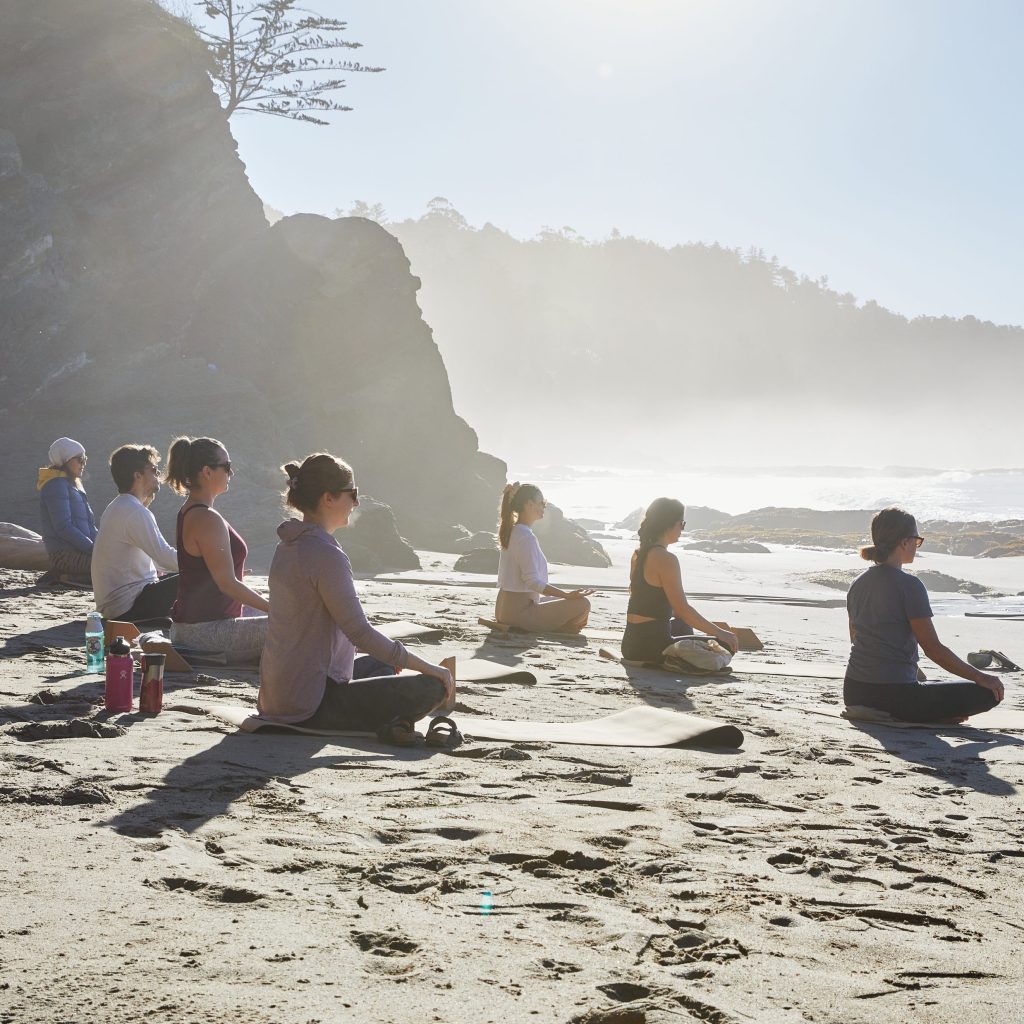 Yoga students in sukasana pose on the beach