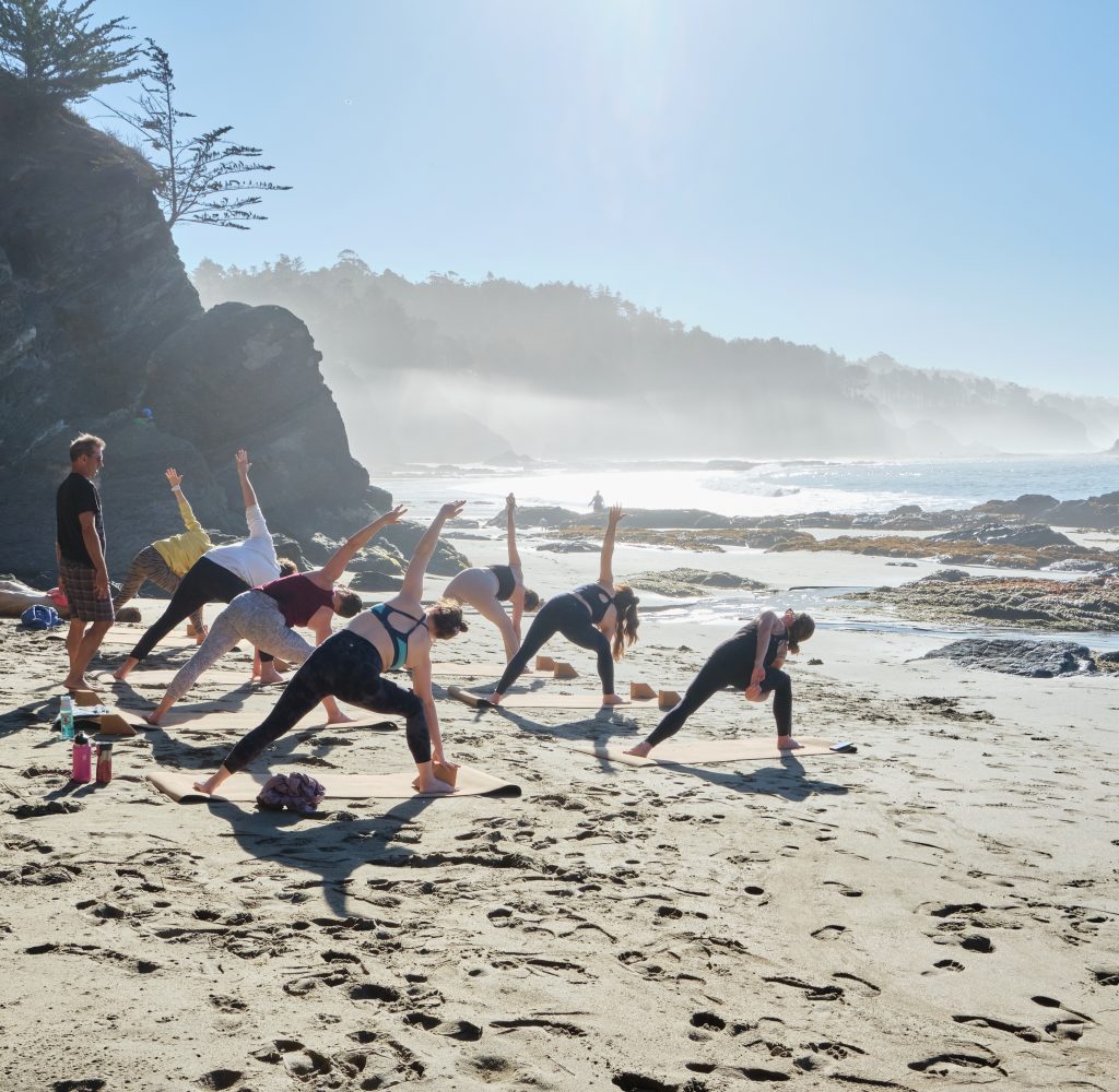 Yoga students in triangle pose on the beach